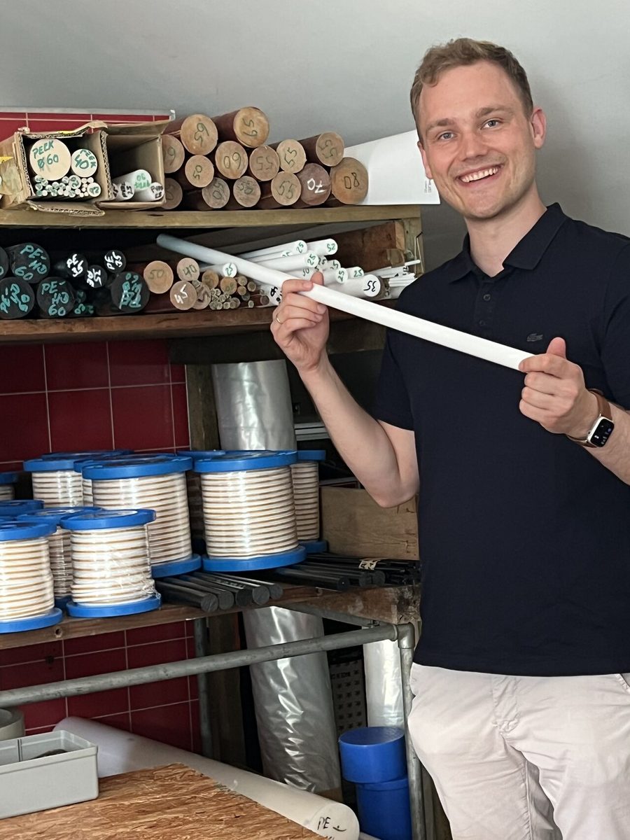 Lukas Hülser mit einem PTFE-Rundstab im Lager der THS Shop GmbH in Mühlacker